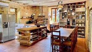 A rustic kitchen with a wooden island, stainless steel appliances, and shelves with dishes.
