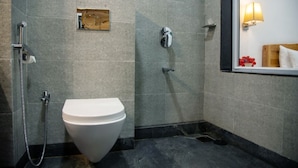 A bathroom with a white toilet, a shower, and a mirror with a wooden frame. - Hotel Kantara (Mawal)