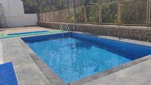 A rectangular swimming pool with a stone wall and a metal fence. - Hotel Kantara (Mawal)