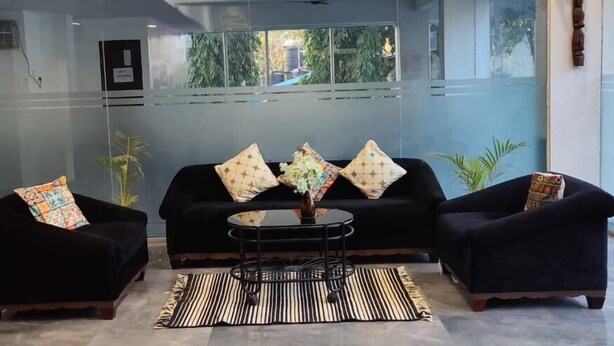 A modern waiting area with a black sofa, two armchairs, a round coffee table, and a striped rug. - Hotel Kantara (Mawal)