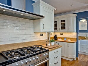 A modern kitchen with white cabinets, a gas stove, and a wooden countertop.