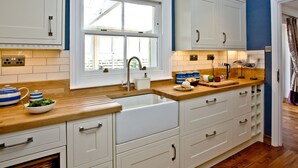 Una cucina con mobili bianchi, un piano di lavoro in legno e una finestra sopra il lavello.