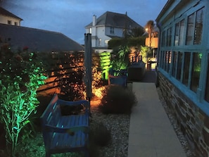 Ein Gartenpfad mit einer Holzbank, einer Pergola und einer Steinmauer.