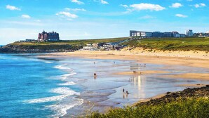 Una spiaggia costiera con un castello e edifici moderni sullo sfondo.