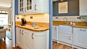 Una cucina con mobili bianchi, un piano di lavoro in legno e un lampadario.
