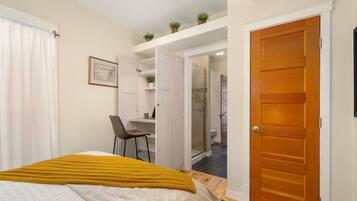 Ein Schlafzimmer mit Bett, Schreibtisch und angrenzendem Badezimmer.