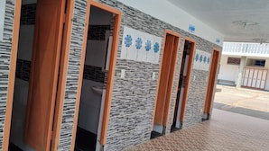 A row of bathroom stalls with a tiled wall and a blue sign indicating the location.