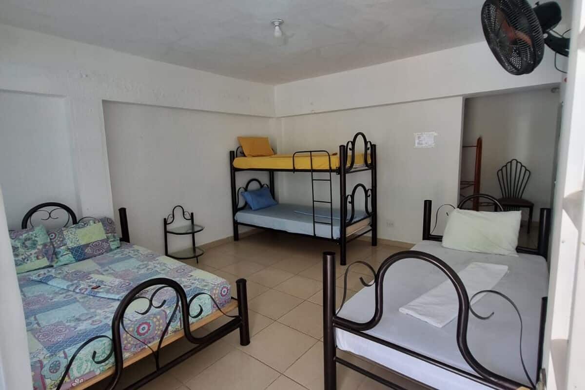 A dormitory room with three bunk beds, a ceiling fan, and a tiled floor.