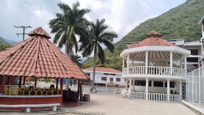 A building with a red-tiled roof, a white balcony, and a surrounding paved area.