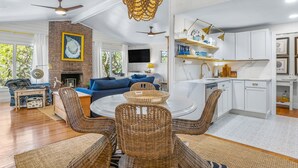 A spacious living room with a dining area, a kitchen, and a fireplace. - Private Pool-Fripp Island-Steps From The Beach (Fripp Island)