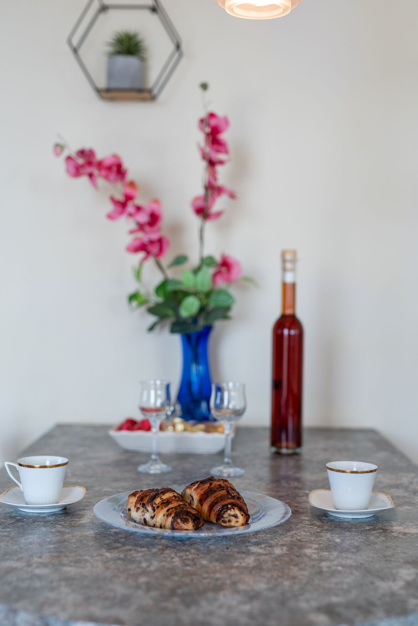 Un tavolo con pasticcini, un vaso di fiori e una bottiglia di vino.
