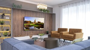 A modern living room with a large flat-screen TV, a chandelier, a sofa, and a coffee table. - The Ultimate 9bd Disney Getaway - The Best Arcade - Private Pool  (Kissimmee)