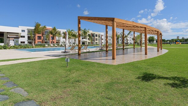 A pool area with a wooden pergola, lounge chairs, and a pool. - Near the beach with pool and gym (Punta Cana)