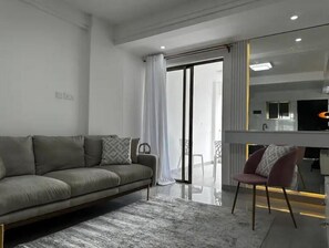 Una sala moderna con un sofá gris, un cojín estampado y una alfombra de mármol.