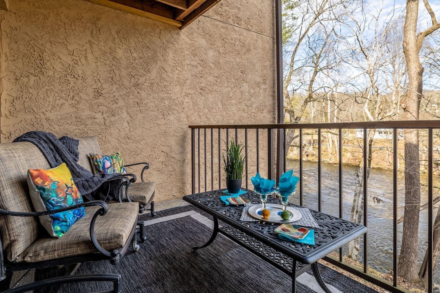 Een balkon met een bank, een tafel en uitzicht op een rivier.