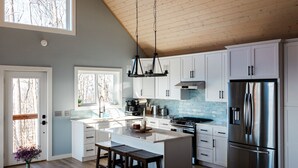 Une cuisine moderne avec des meubles blancs, un réfrigérateur en acier inoxydable et un grand îlot central doté de tabourets.