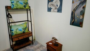 Una cama litera con almohadas verdes, una mesita con un adorno y dos obras de arte en la pared.