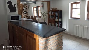 Una cocina con una isla central, microondas, un armario y una ventana con persianas.