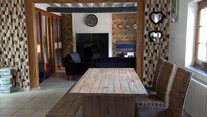 Un comedor amplio con una mesa de madera y sillas de mimbre, una pared de piedra con patrones geométricos y un refrigerador Samsung.