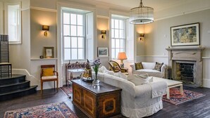 A spacious living room with a white sofa set, a wooden coffee table, and a fireplace. - House of the Northern Gate (Thurso)