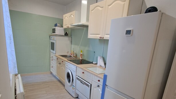 Een kleine keuken met een wasmachine, een koelkast en een magnetron.
