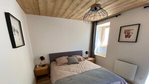 A bedroom with a bed, nightstands, a window, and a ceiling light fixture.