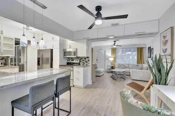 A modern kitchen with a central island, built-in appliances, pendant lighting, and a ceiling fan.