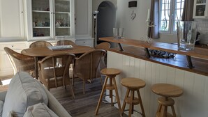 Una cuina moderna amb armaris blancs, un taulell de bar de fusta i cadires de vimet.