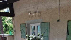 Zona de menjador a l'aire lliure coberta, amb taula de vidre i cadires de vimet.