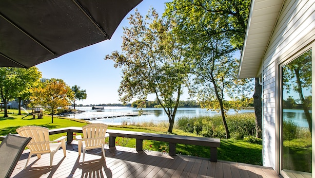 A deck with chairs and a bench overlooking a lake. - Serene Lakefront Home On Lake Minnetonka (Excelsior)