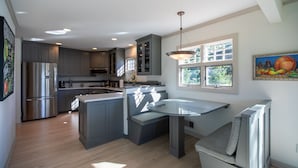 A modern kitchen with grey cabinets, a stainless steel refrigerator, and a built-in island with seating. - Serene Lakefront Home On Lake Minnetonka (Excelsior)
