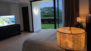 Ein modernes Schlafzimmer mit Fernseher, einem großen Bett, einem Deckenventilator und Blick ins Freie.