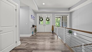 Un couloir doté d’un plancher en bois, de murs blancs et d’une rambarde en verre.