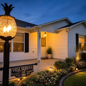A house with a well-lit entrance, a sign reading 'VIDA SURENA EST. 2024,' and a decorative street lamp. - Private Pool Oasis + Hot Tub ,Quiet Luxury in The Villages, Pet Friendly (The Villages)
