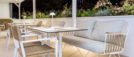 An outdoor patio with white furniture, including a sofa and chairs, and a table.
