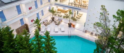 Una piscina interior con zonas de descanso, un comedor y una escalera que lleva a los pisos superiores.