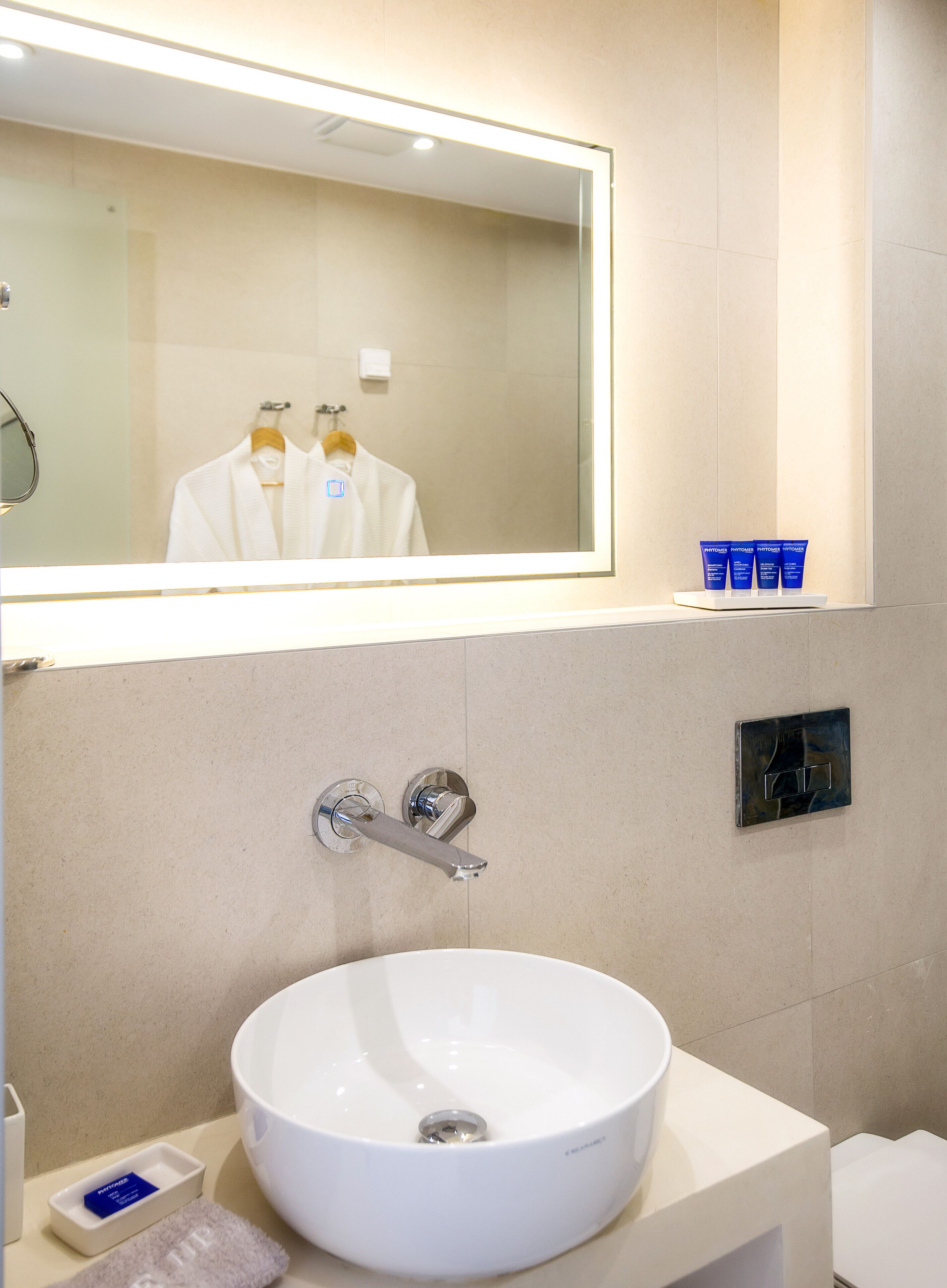 A modern bathroom with a large mirror, a white sink, and a towel rack.