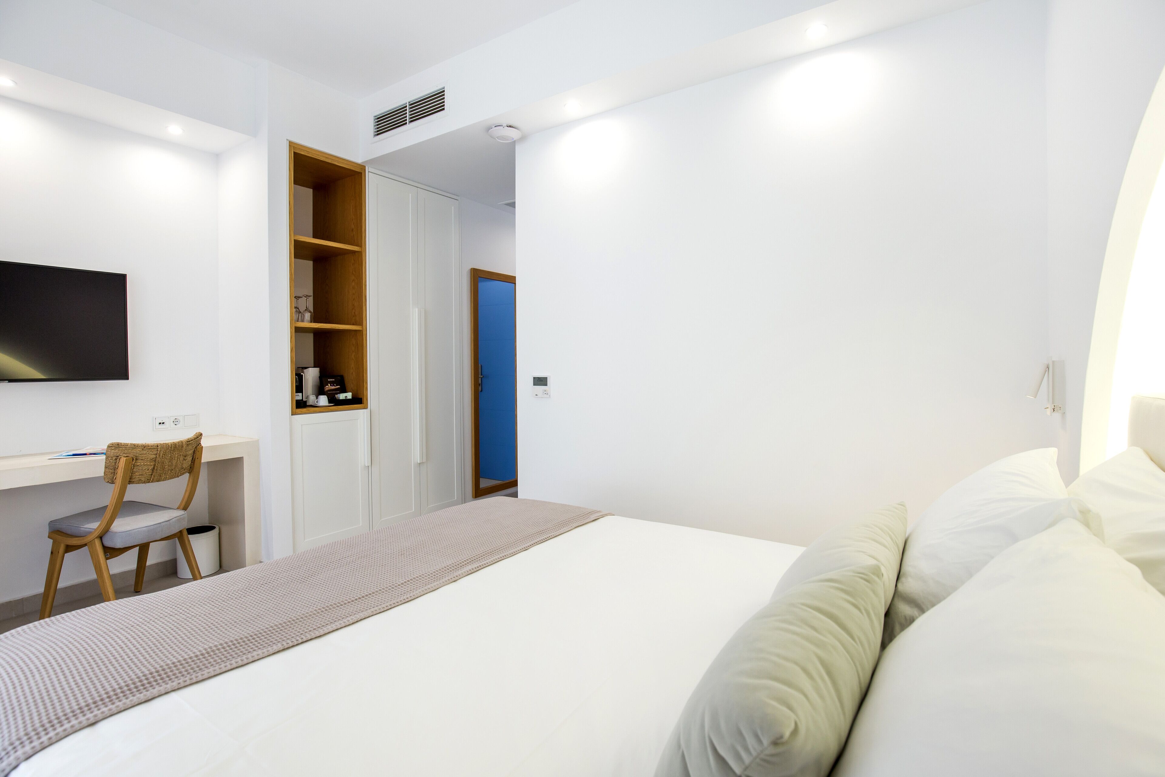A bedroom with a bed, a desk, and a chair.