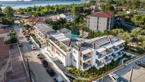 Un hôtel moderne à plusieurs étages, doté de balcons, d’une piscine et offrant une vue sur la mer et les montagnes.