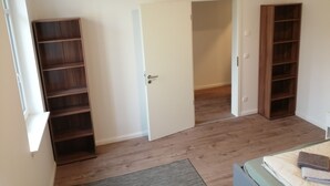 A room with a wooden floor, a white door, and two wooden shelves. - Komfortable Ferienwohnung mit Parklplatz (Zossen)