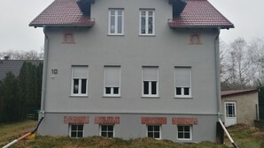 A two-story building with a grey facade, red-tiled roof, and six windows with shutters. - Komfortable Ferienwohnung mit Parklplatz (Zossen)