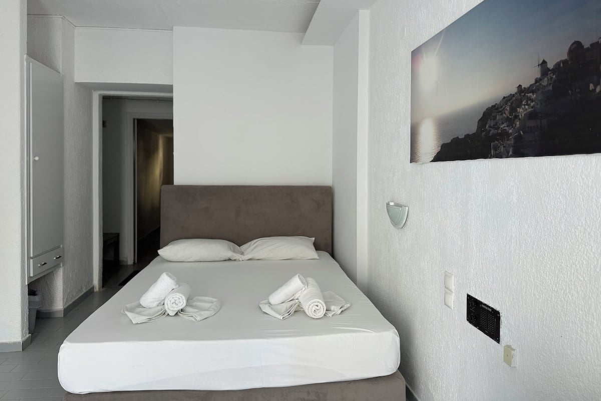 A modern hotel room with a large bed, a view of a coastal landscape, and a minimalist design.