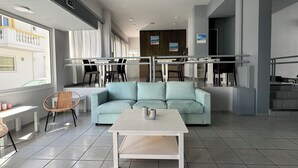 A modern interior with a light blue sofa, a white coffee table, and a dining area with chairs and a table. - Simple Hotel Hersonissos Blue (Hersonissos)