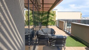 A covered outdoor seating area with wicker furniture and a glass wall overlooking a green space. - Trstevere Boutique Suite Roma with Turkish bath (Roma)
