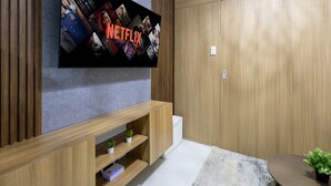 Un salon moderne avec un téléviseur à écran plat fixé au mur, sur lequel est affiché le logo de Netflix.