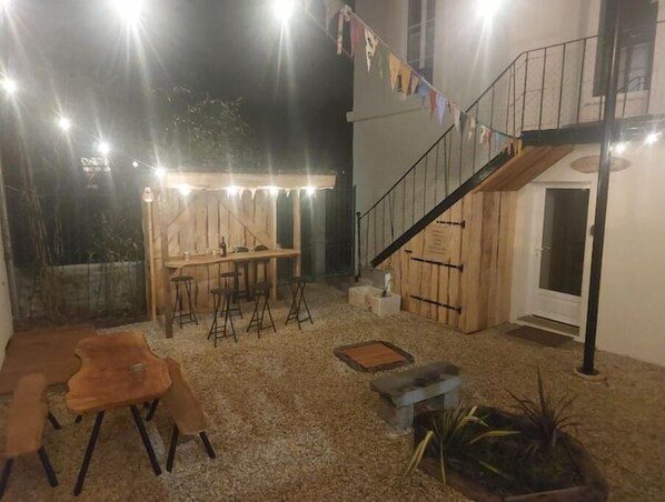 An outdoor patio area with a wooden table and chairs, a small staircase, and a potted plant.