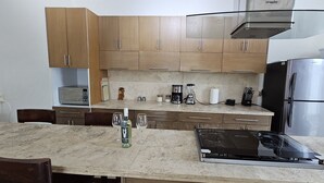 Una cocina con armarios de madera, una encimera con licuadora, cafetera y refrigerador.