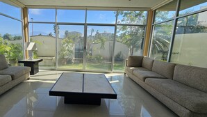 Una sala de estar moderna con una pared de vidrio, dos sofás, una mesa de centro y una lámpara.