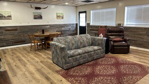 Une pièce avec un plafond en bois, une table à manger avec des chaises, un canapé, un fauteuil en cuir et un tapis à motifs.