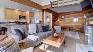 A spacious living area with a sofa, coffee table, and a staircase leading to an upper level. - Ski in Ski out, Amazing Views Condo in East Village VP211 (Copper Mountain)